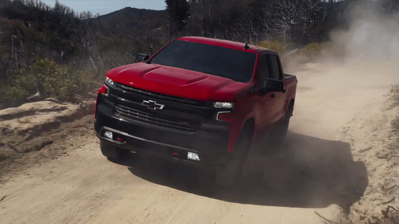 a red truck driving down a dirt road