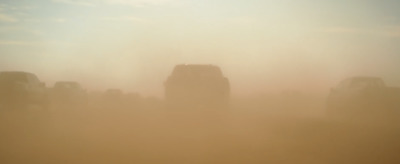 a group of trucks driving through a foggy field