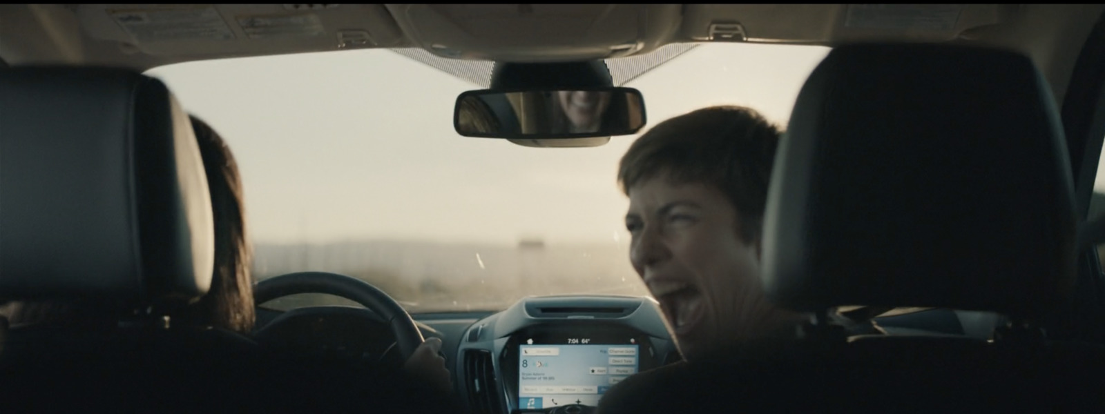 a woman driving a car with a cell phone in her hand