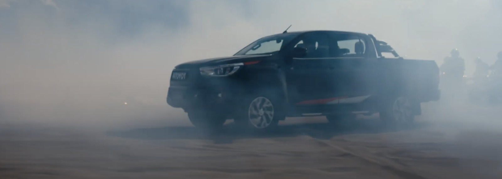 a black truck driving down a dirt road