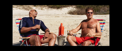 two men sitting in lawn chairs on a beach