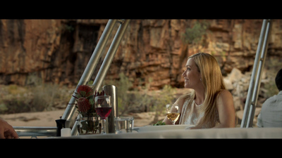 a woman sitting at a table with a glass of wine