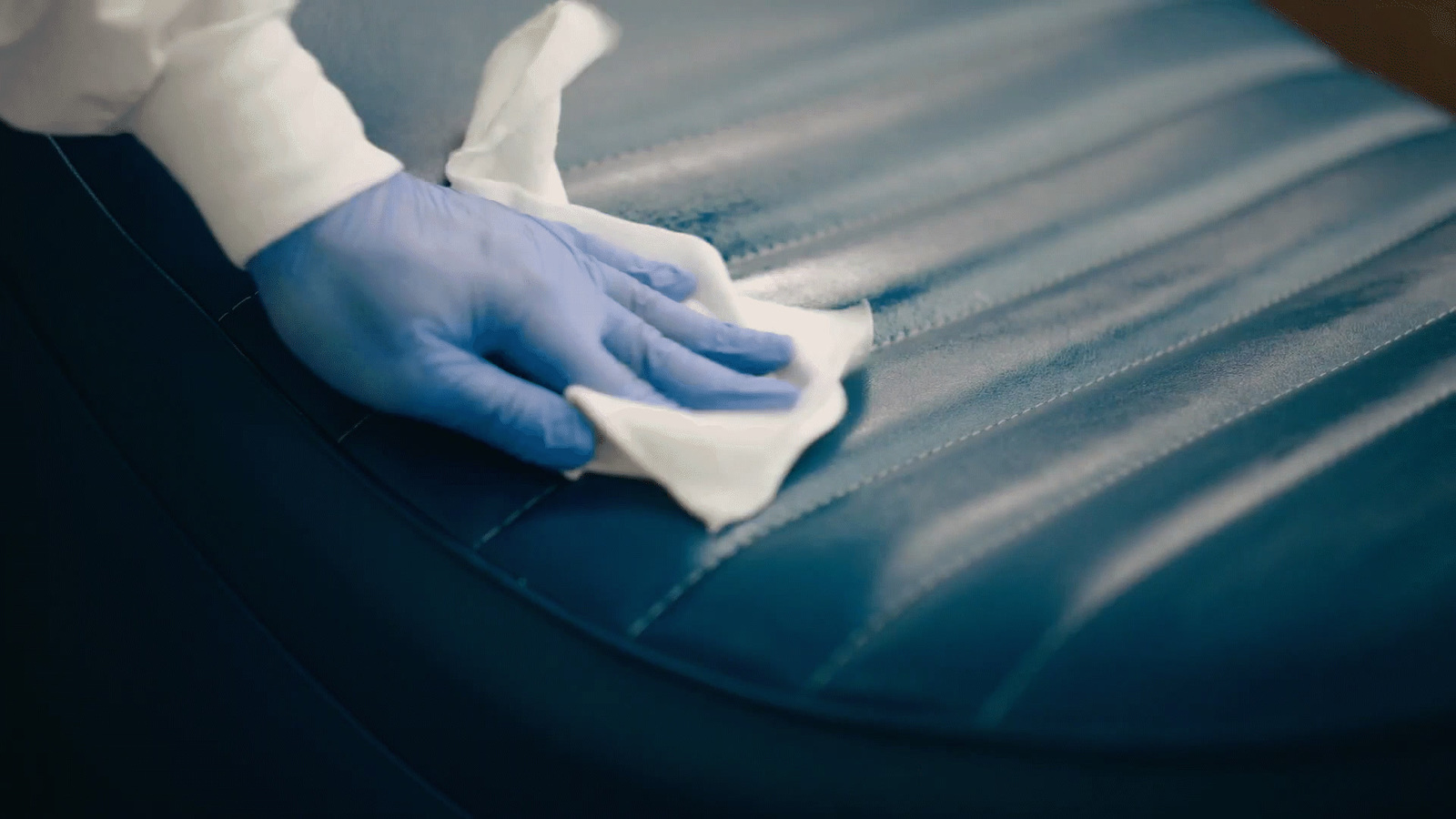 a person with blue gloves and gloves cleaning a couch