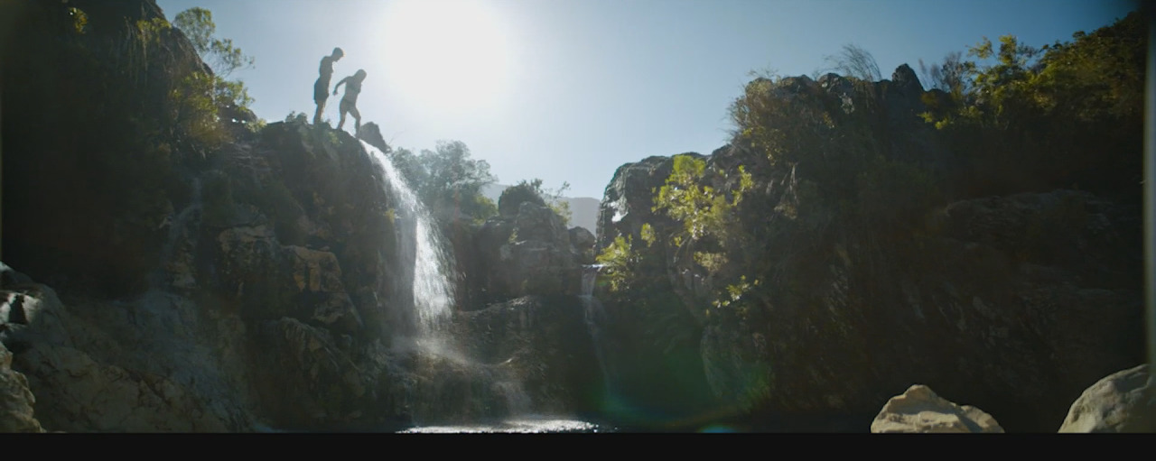 a group of people jumping off of a waterfall