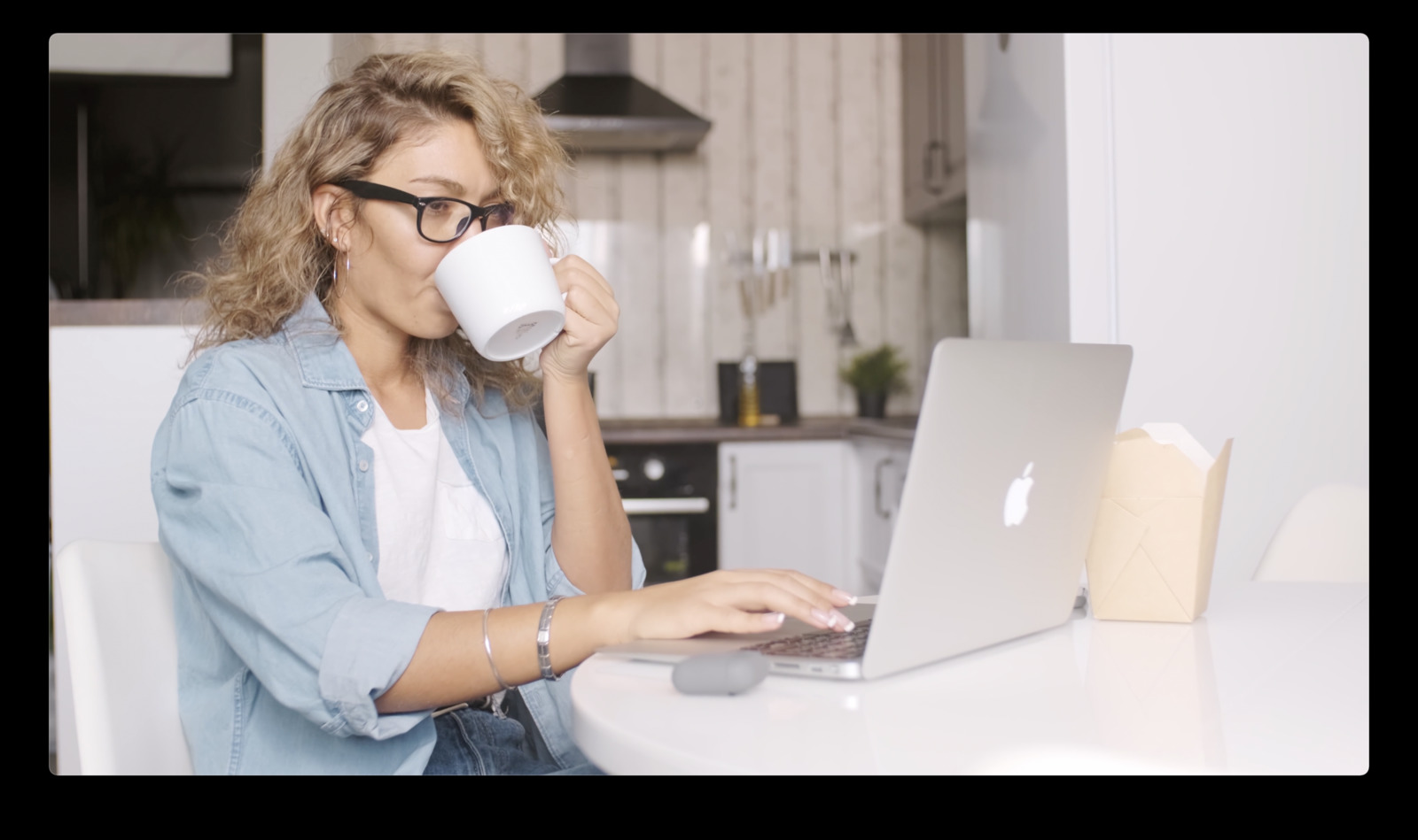 a woman drinking coffee while using a laptop computer