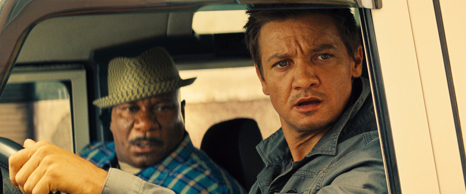 a couple of men sitting in a car next to each other