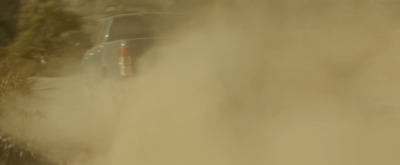 a truck driving down a road covered in dust