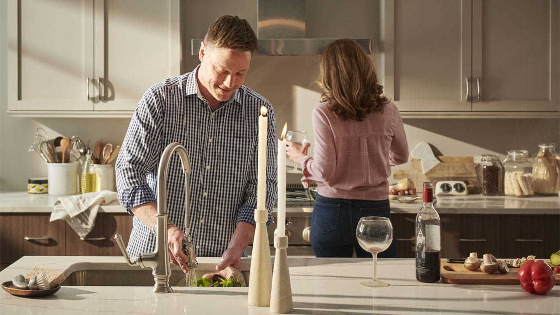 a man and woman in a kitchen preparing food