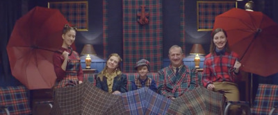 a group of people sitting on a couch with umbrellas