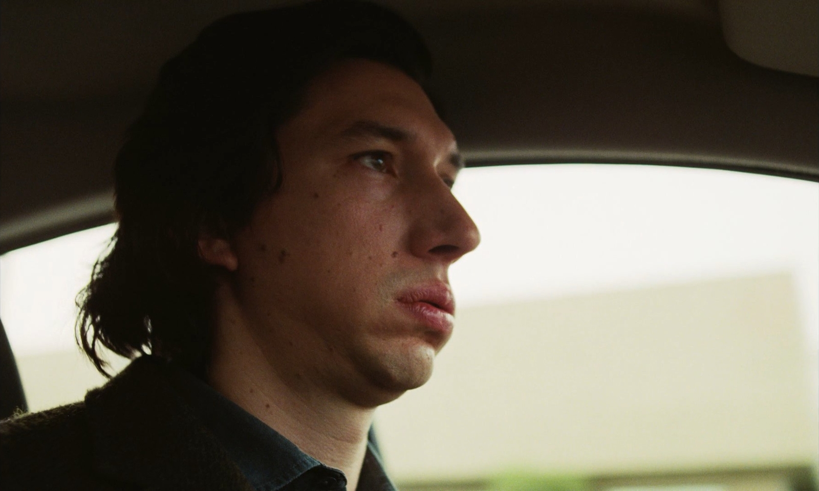 a man sitting in a car looking out the window