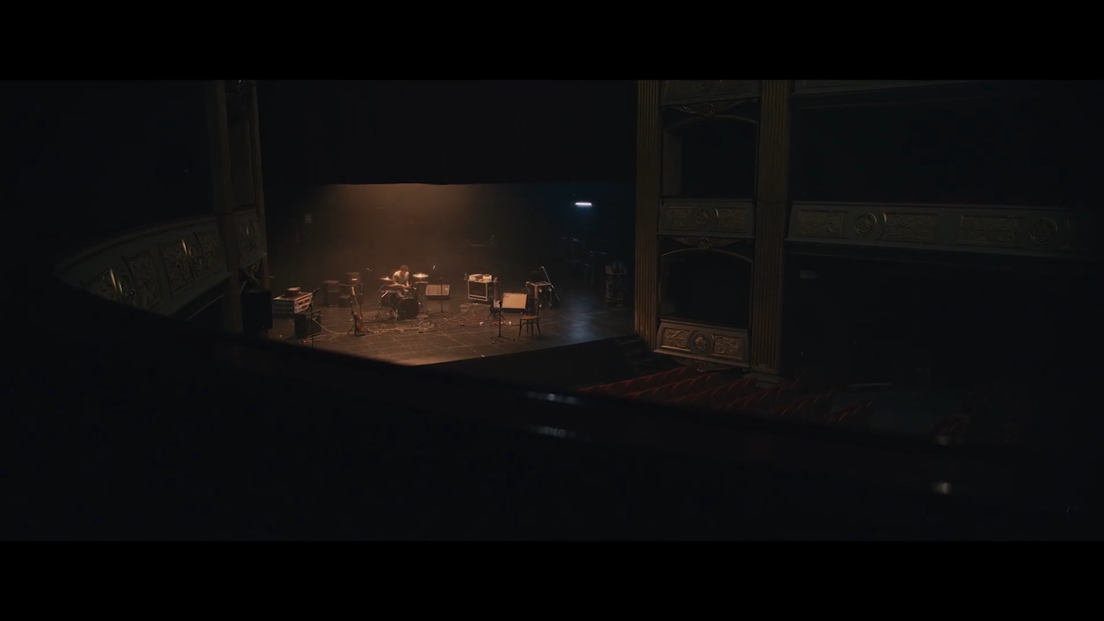 a dark stage with chairs and a piano