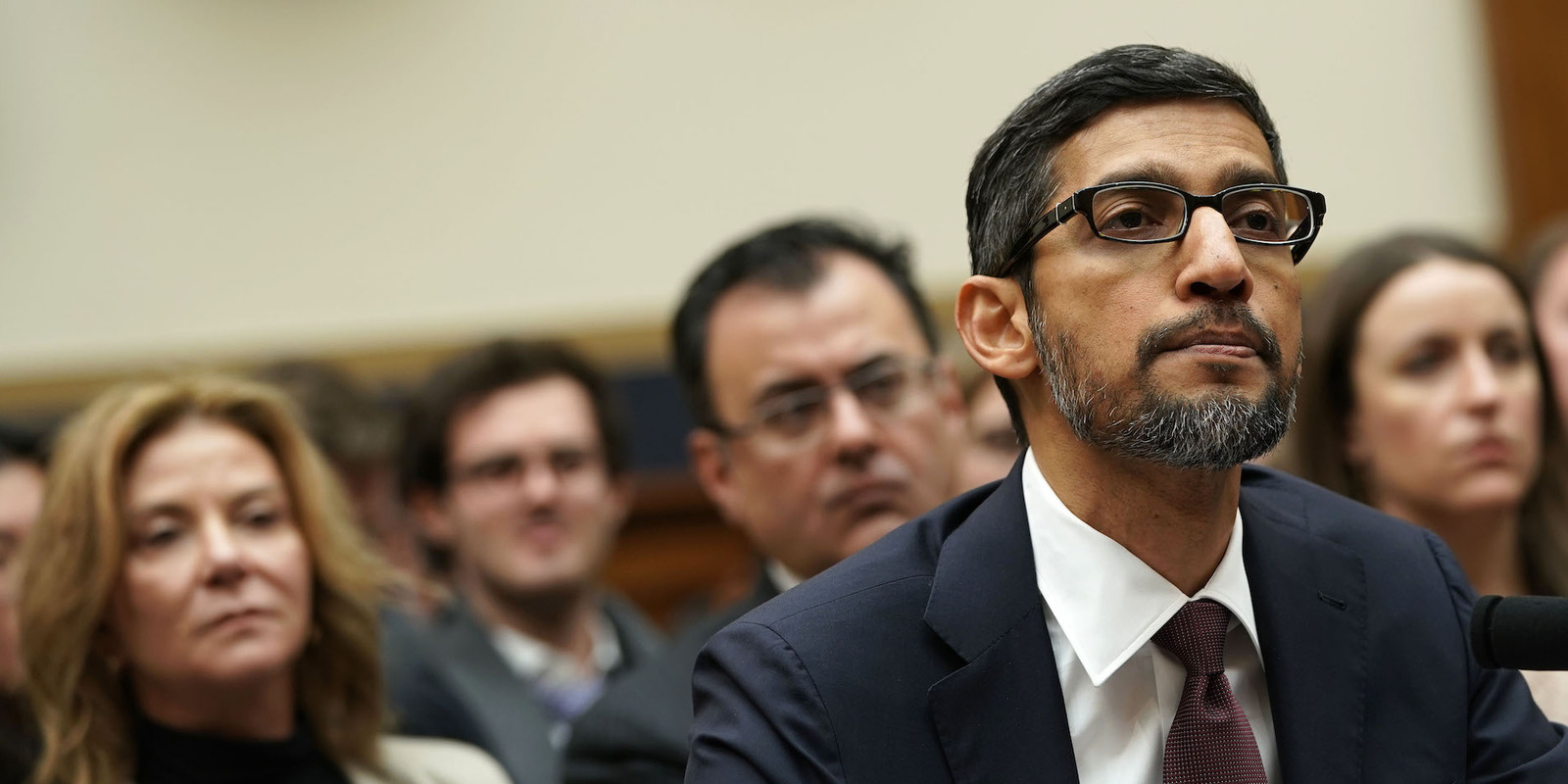 a man in a suit and tie sitting in front of a microphone