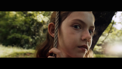 a young girl holding onto a rope in a forest