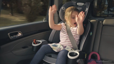 a little girl sitting in a car seat with her hands up