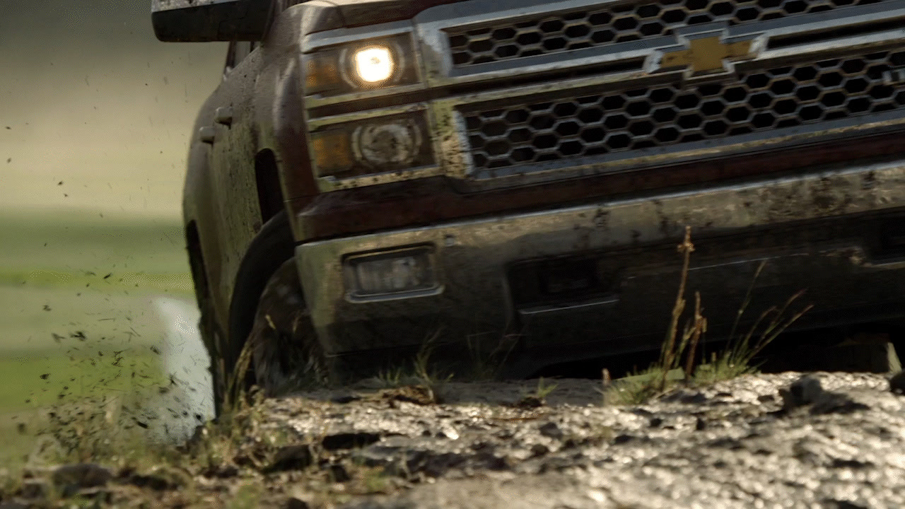 a black truck driving down a dirt road