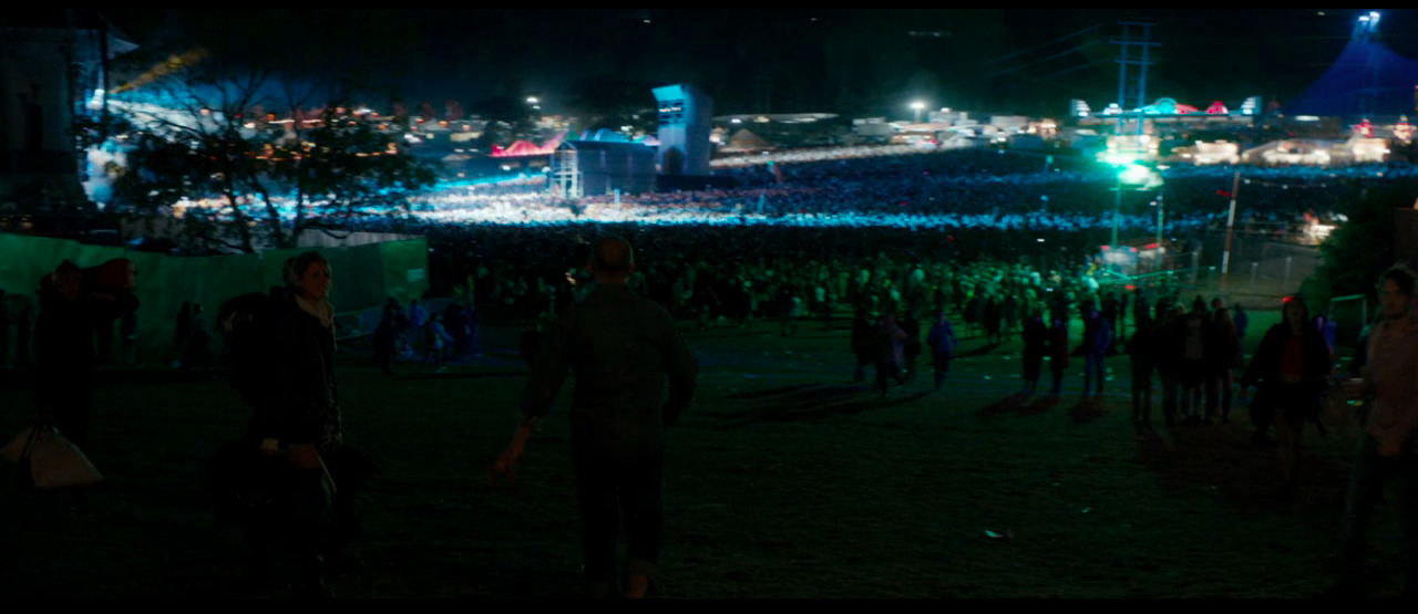 a crowd of people standing around a field at night