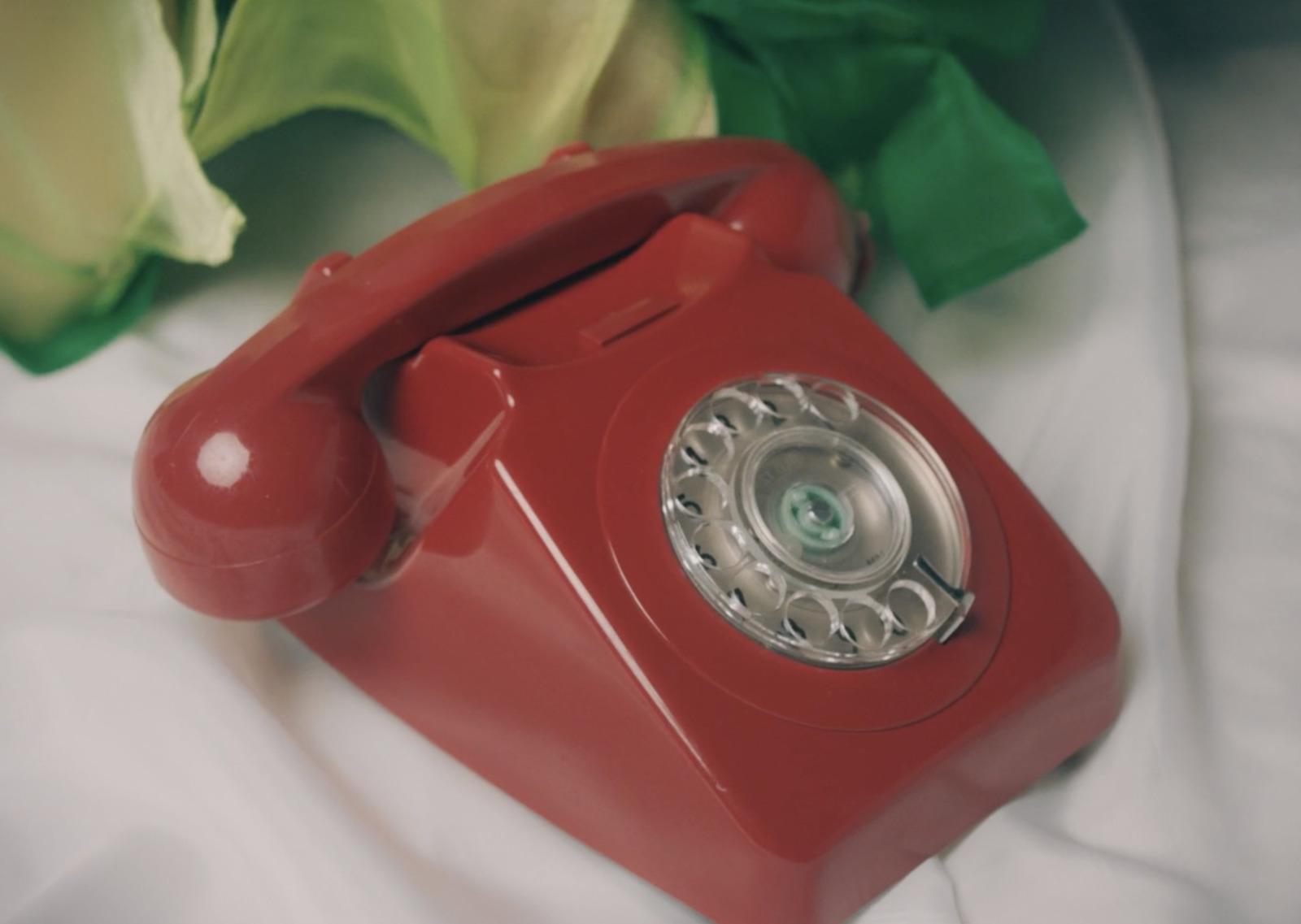 a red phone sitting on top of a white sheet