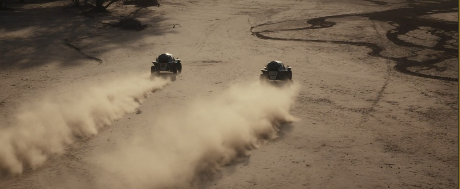 a couple of cars driving down a dirt road