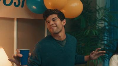 a man holding a cup in front of balloons