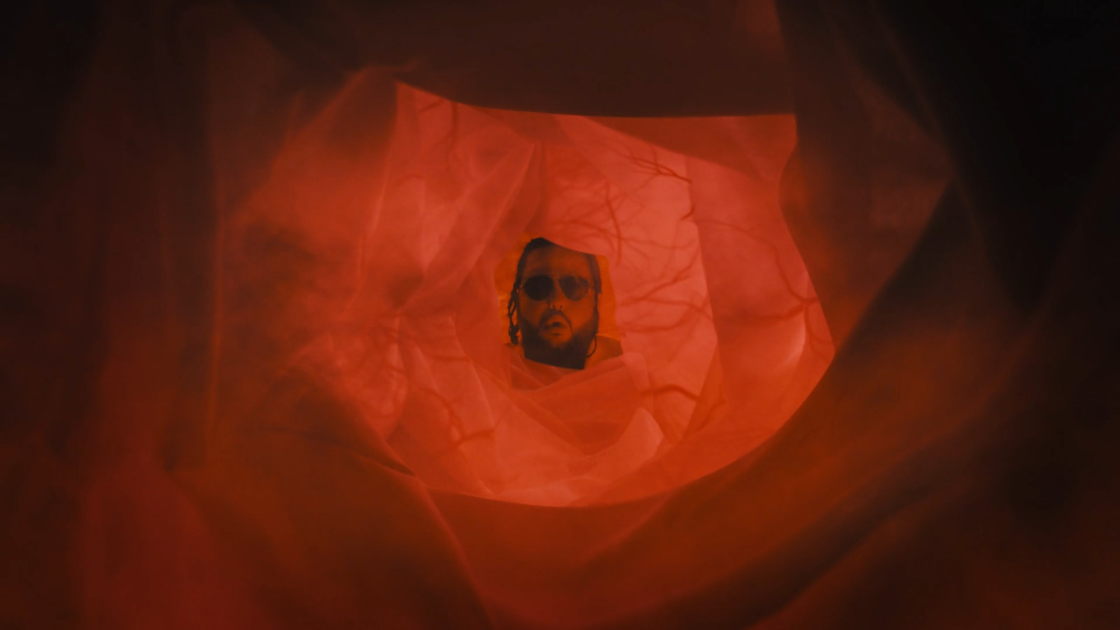 a man's face is seen through a red cloth