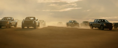 a group of trucks driving down a dirt road