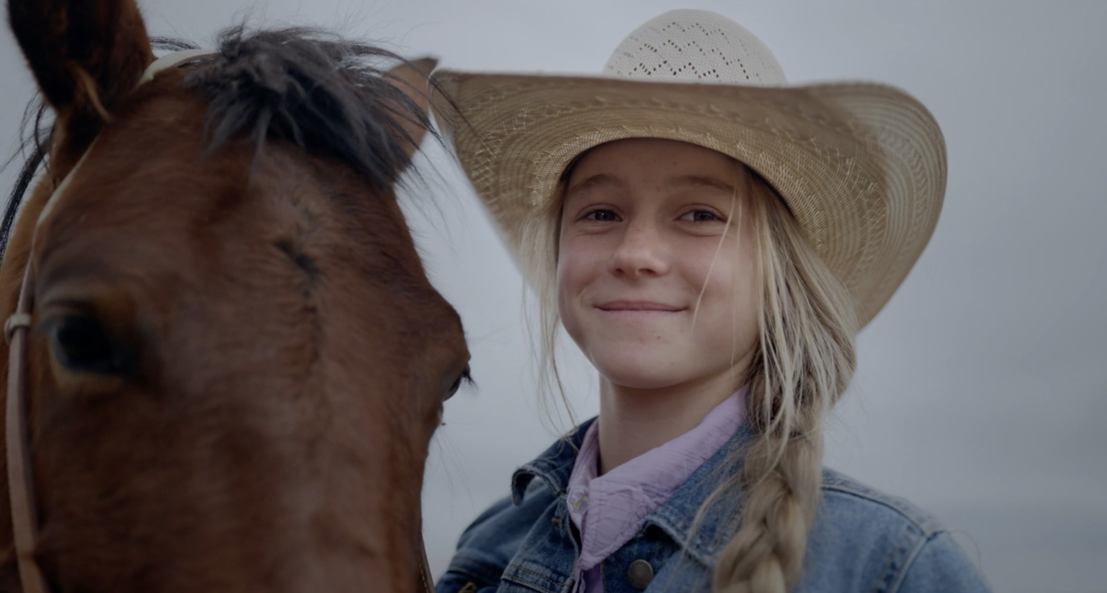 a girl wearing a cowboy hat standing next to a horse