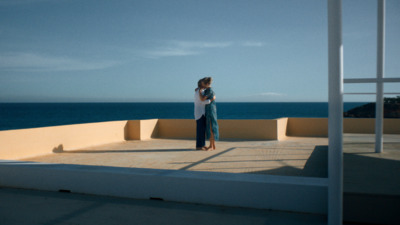 a woman standing on a balcony next to the ocean