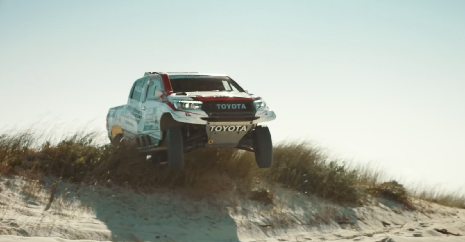 a toyota truck driving up a sand dune