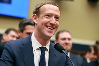 a man in a suit and tie smiles as he speaks into a microphone