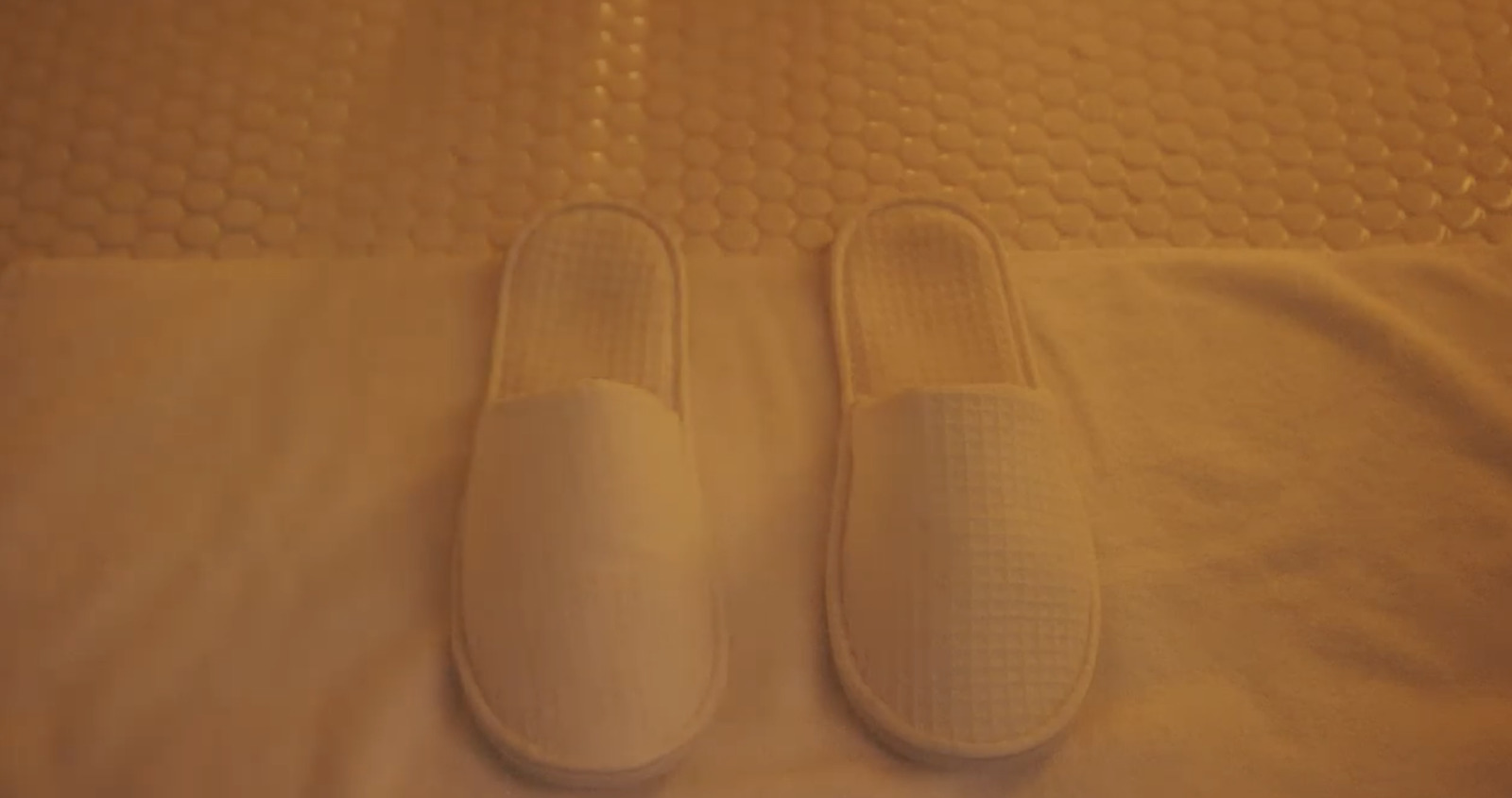 a pair of white slippers sitting on top of a bed