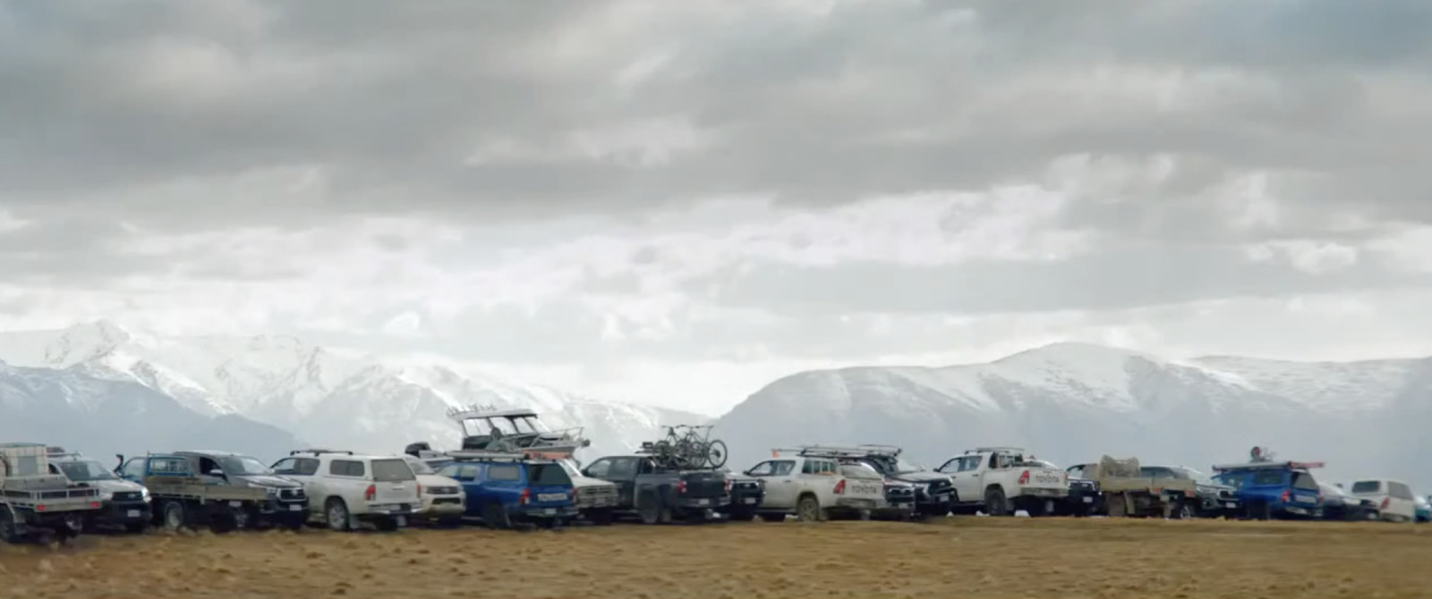 a group of trucks parked in a field with mountains in the background