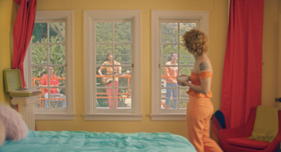 a woman standing in front of a bed in a bedroom