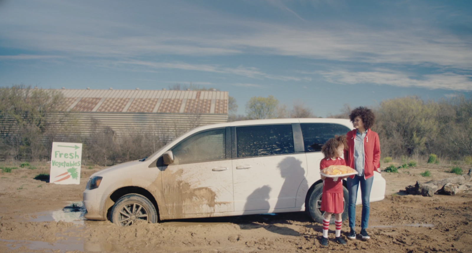 a woman and a child standing next to a white van