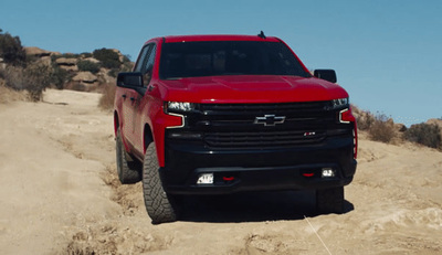 a red truck driving down a dirt road