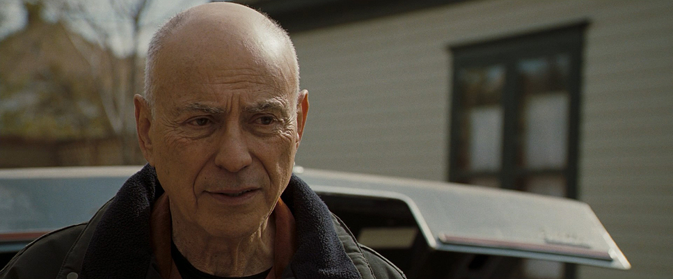 an older man standing in front of a car