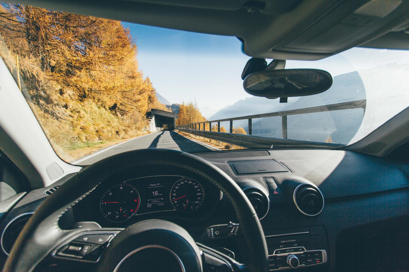 a car driving down a road next to a forest