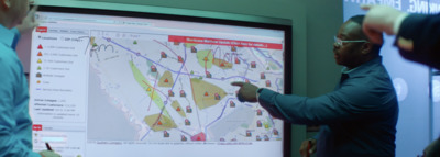 a man pointing to a map on a large screen