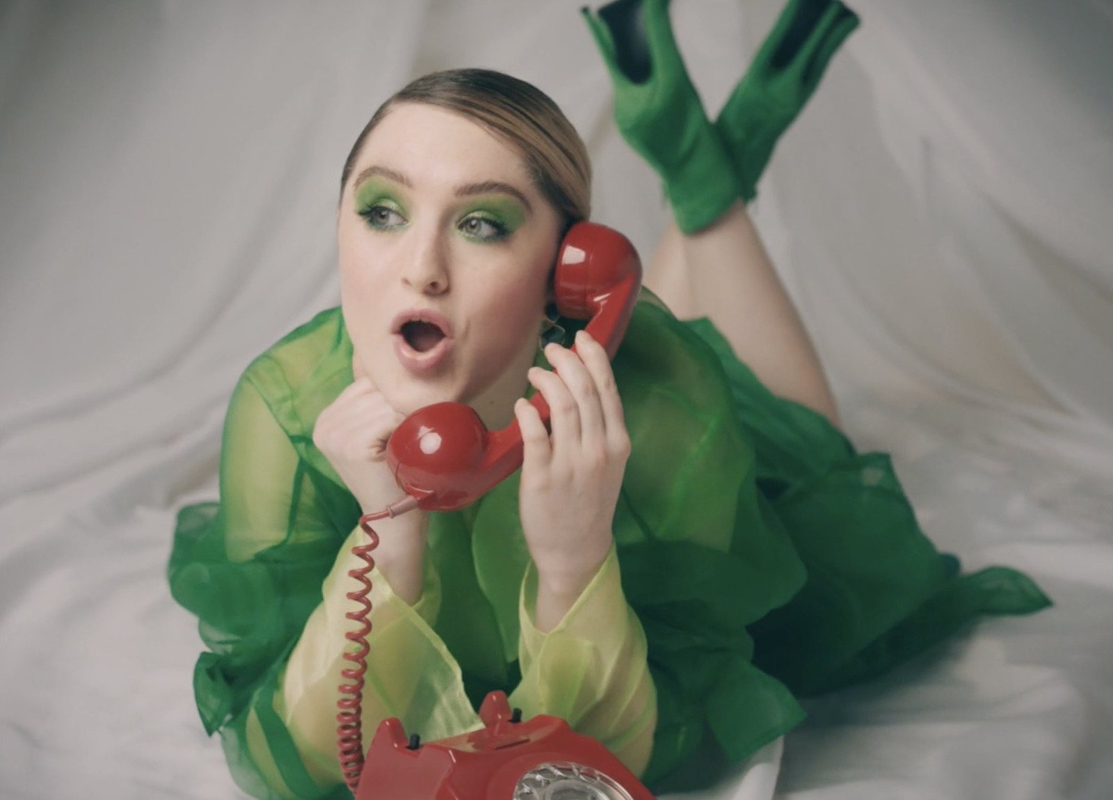 a woman in a green dress talking on a red phone