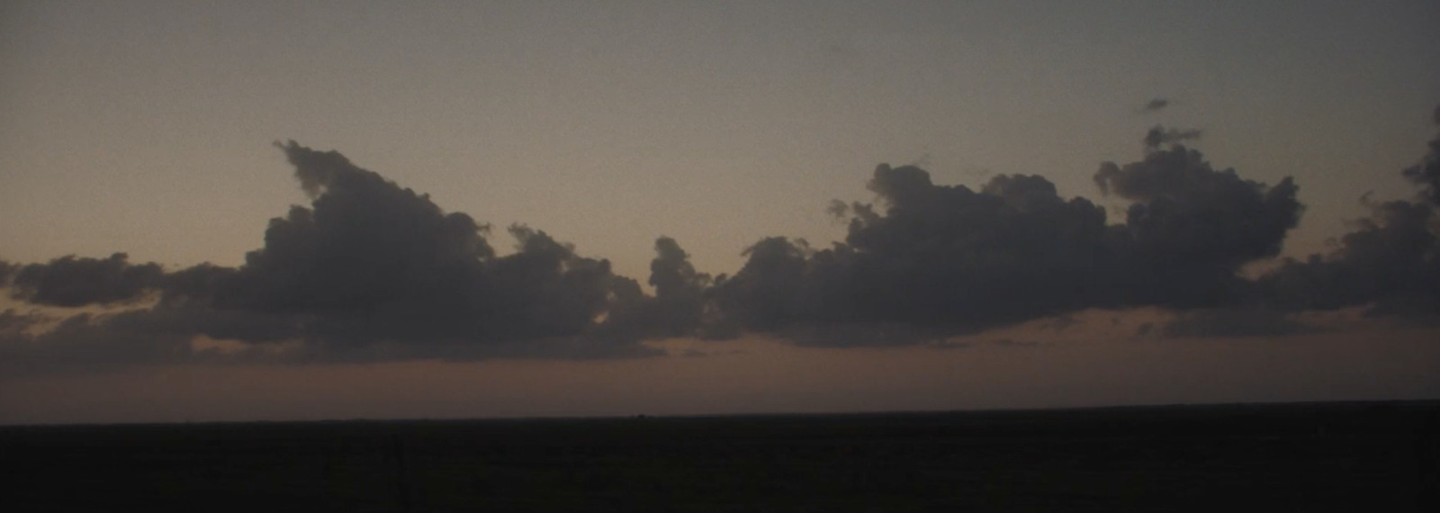 a plane flying through a cloudy sky at dusk