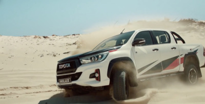 a white truck driving through a desert filled with sand