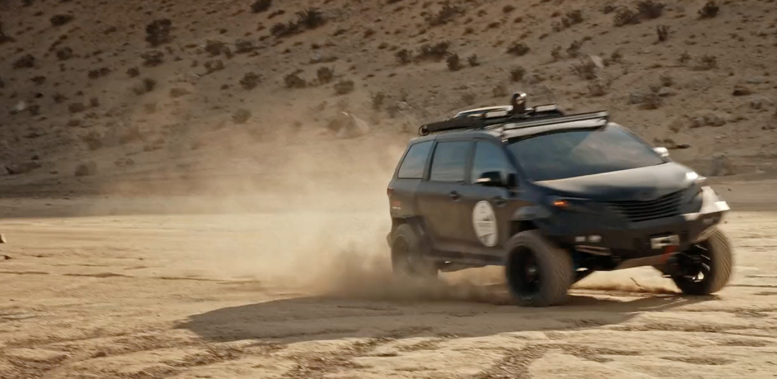 a black vehicle driving on a dirt road