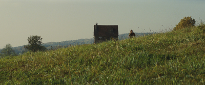 a person standing on a hill with a house in the background