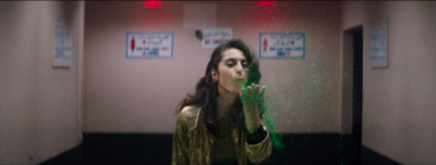 a woman standing in a room with green powder on her face