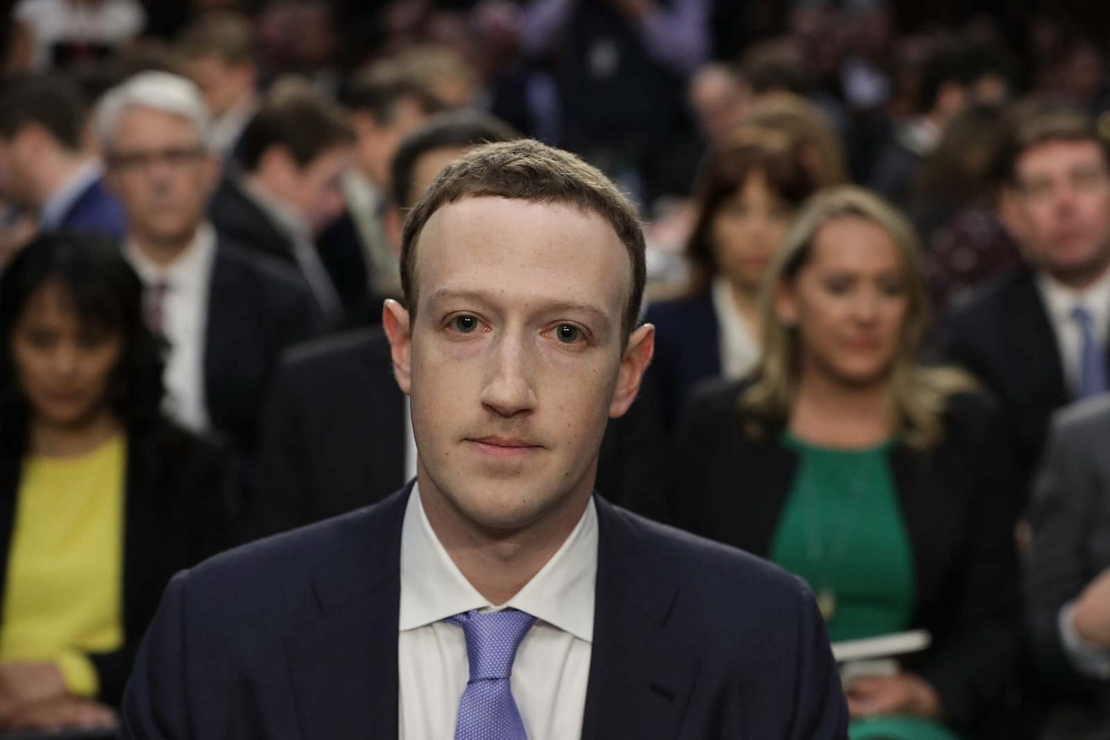 a man in a suit and tie standing in front of a crowd of people