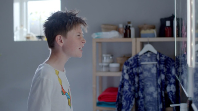 a young boy standing in front of a closet