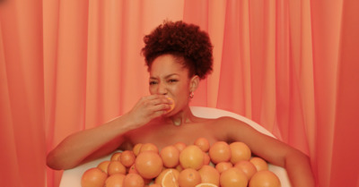 a woman sitting in a bathtub covered in oranges