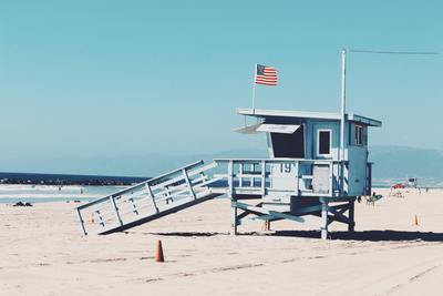 a lifeguard tower on the beach with an american flag on top