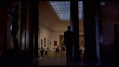 a man standing in a hallway between two pillars