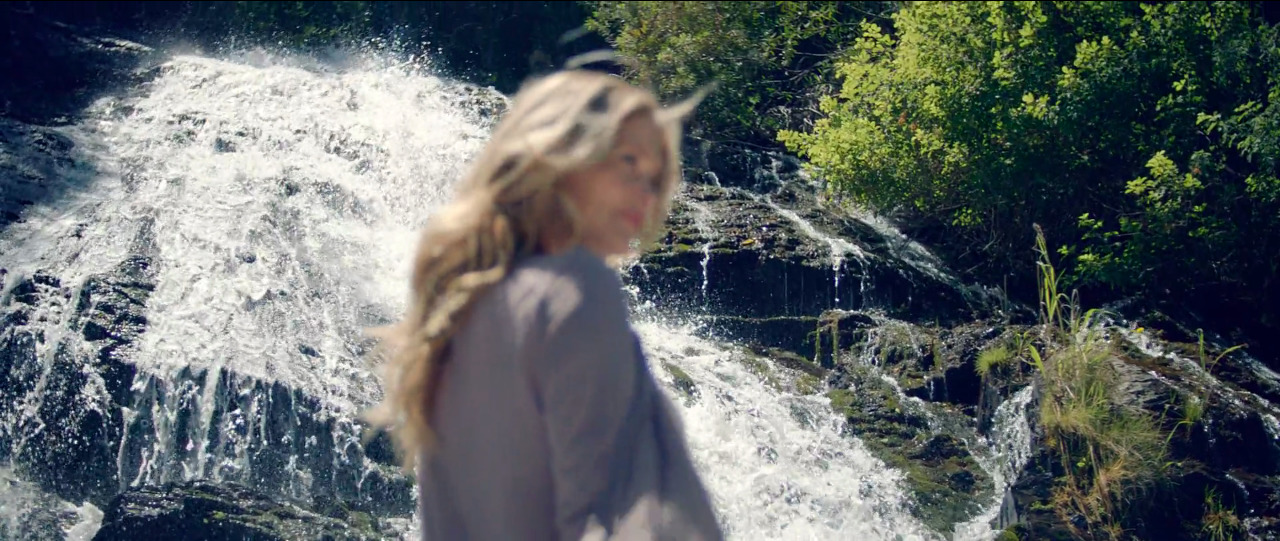 a woman standing in front of a waterfall