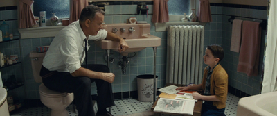 a man sitting on a toilet next to a little boy